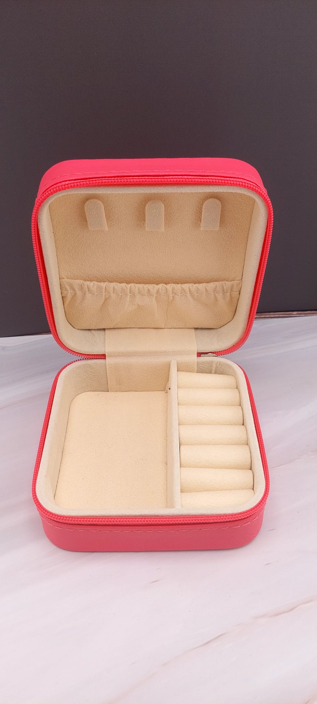 A square jewelry box made of black material with a beige interior, featuring compartments for organizing jewelry.