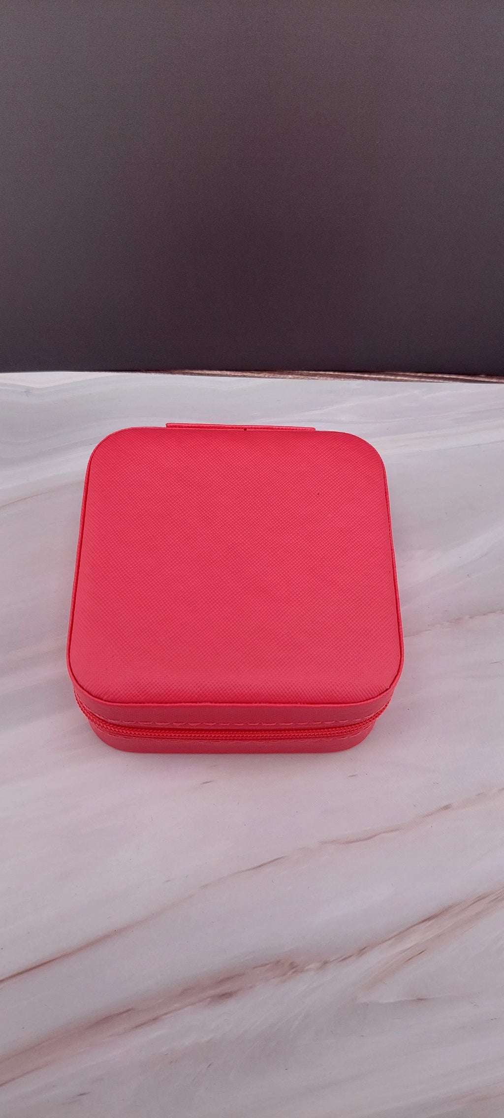A square jewelry box made of black material with a beige interior, featuring compartments for organizing jewelry.