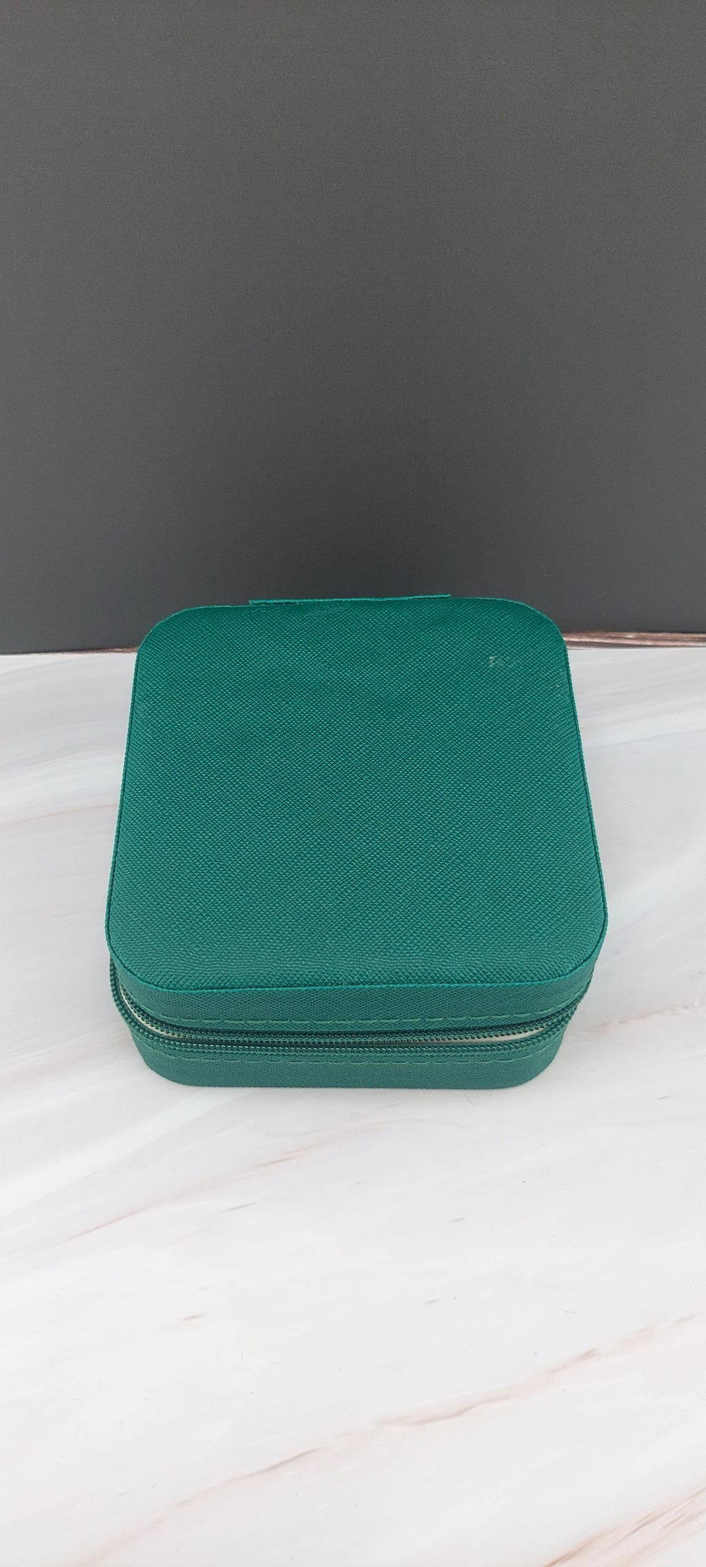 A square jewelry box made of black material with a beige interior, featuring compartments for organizing jewelry.