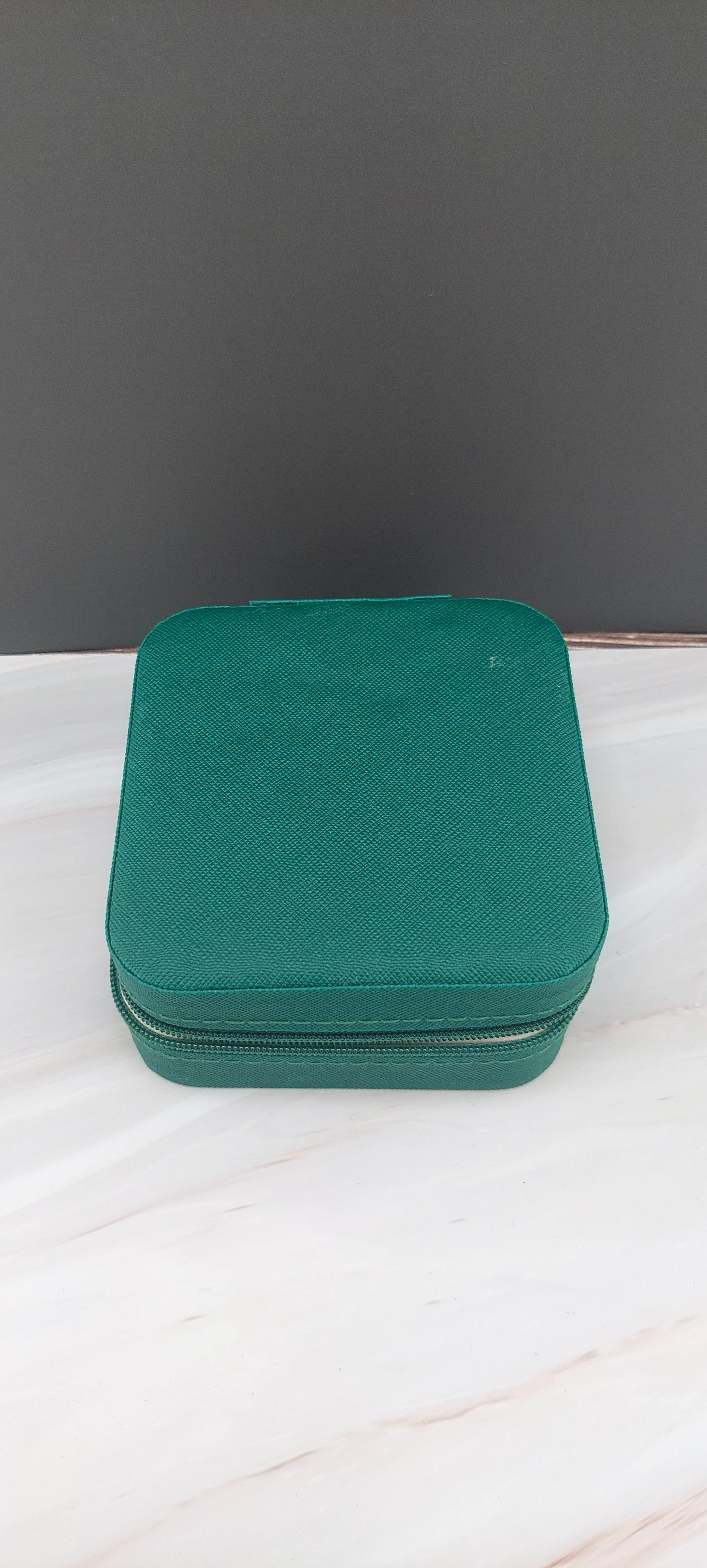 A square jewelry box made of black material with a beige interior, featuring compartments for organizing jewelry.
