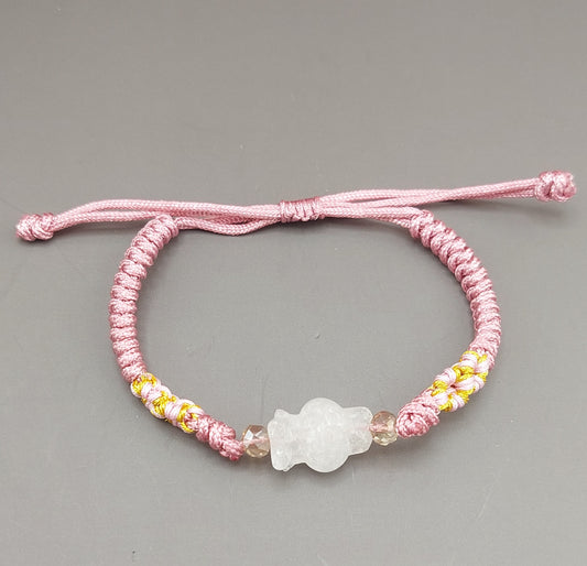 A pink and yellow bracelet with a white floral charm, displayed against a grey background