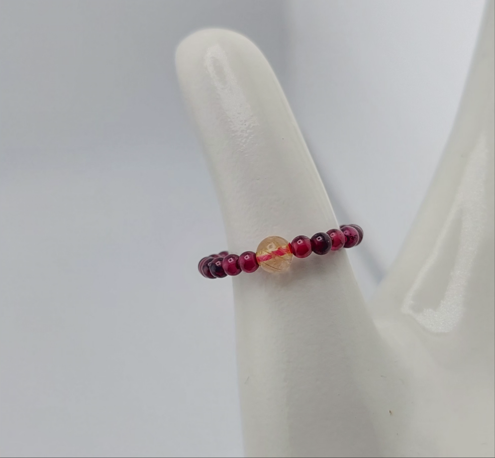 A ring with red and orange beads displayed on a white mount.