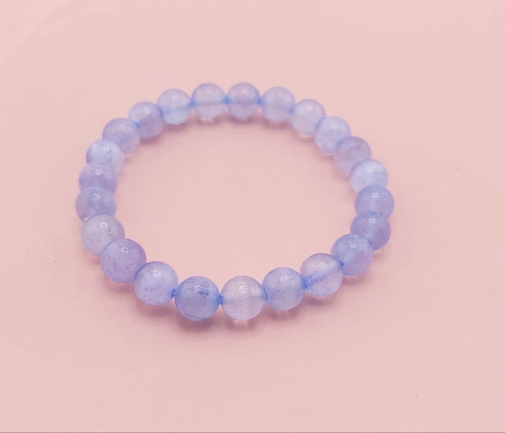 A yellow beaded bracelet on a pink background.