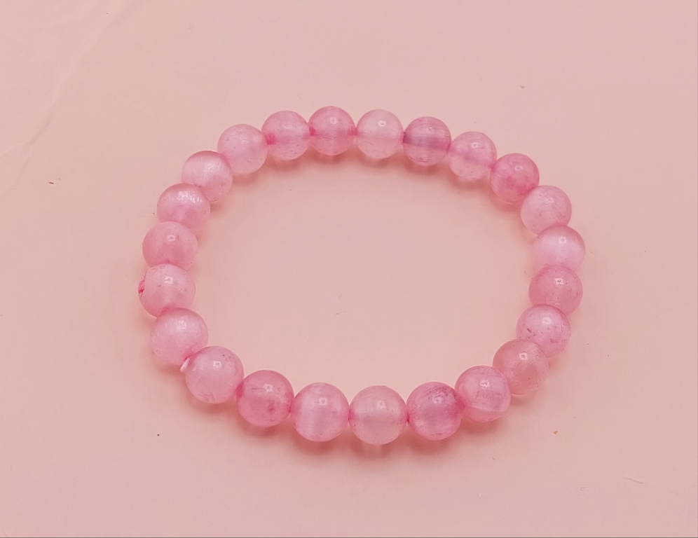 A yellow beaded bracelet on a pink background.