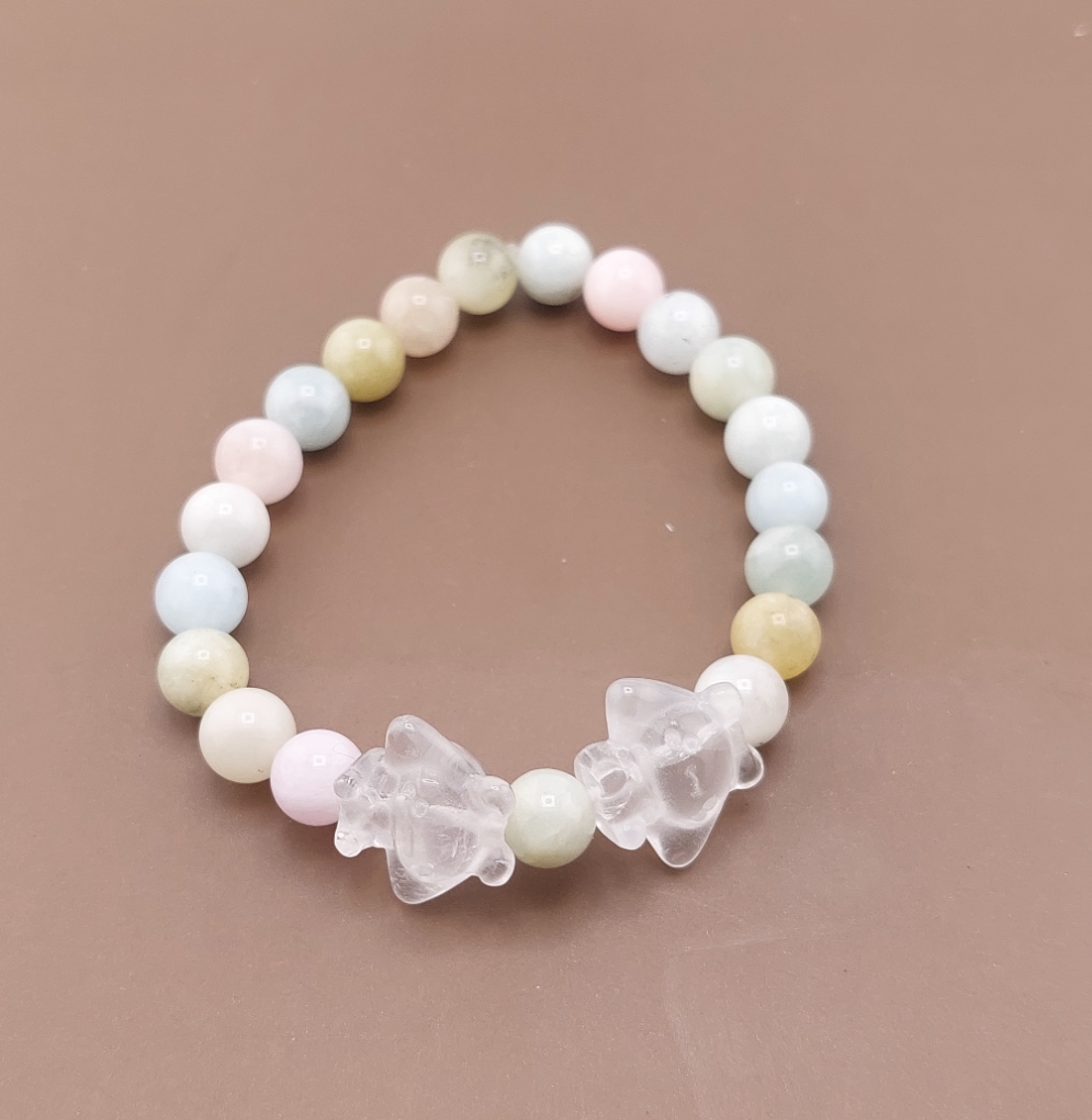 A bracelet with round beads in shades of pink, green, and white, featuring two bear charms.