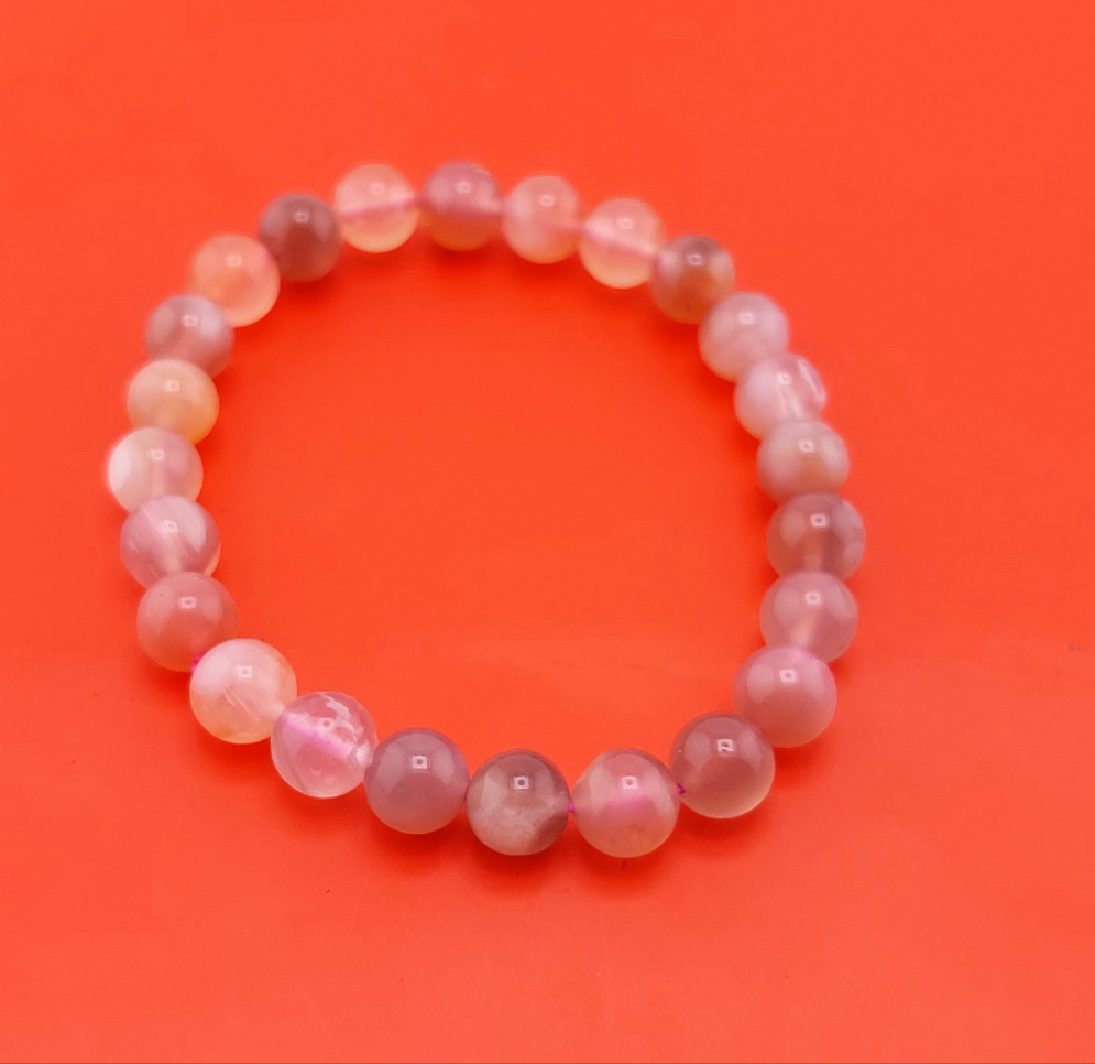 A multicolored beaded bracelet laid out on a red surface.