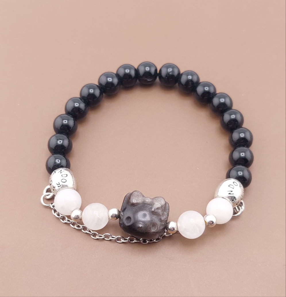 A Hello Kitty themed bracelet with black and silver obsidian beads, white accents, and a silver Hello Kitty charm.