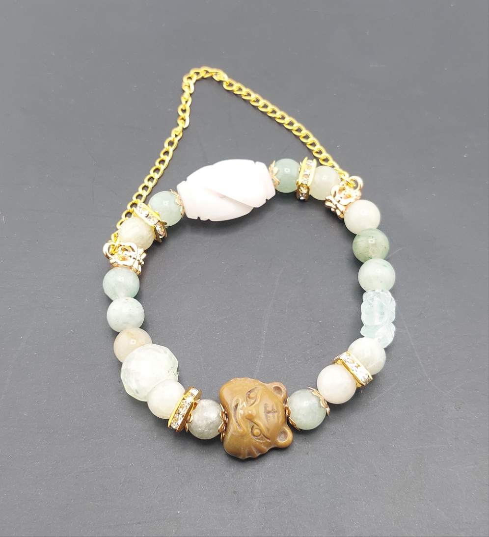 A bracelet featuring round light green beads, a gold-colored chain, and a gold-colored tiger-shaped charm.