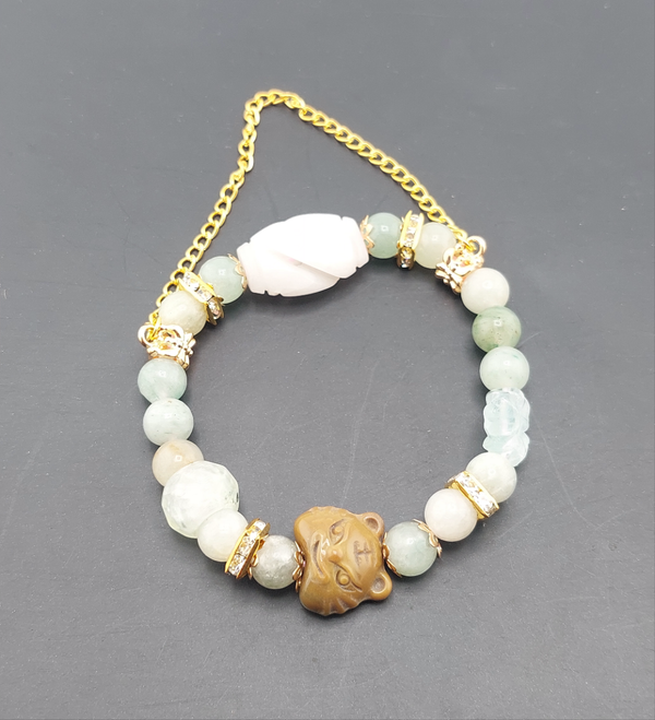 A bracelet featuring round light green beads, a gold-colored chain, and a gold-colored tiger-shaped charm.