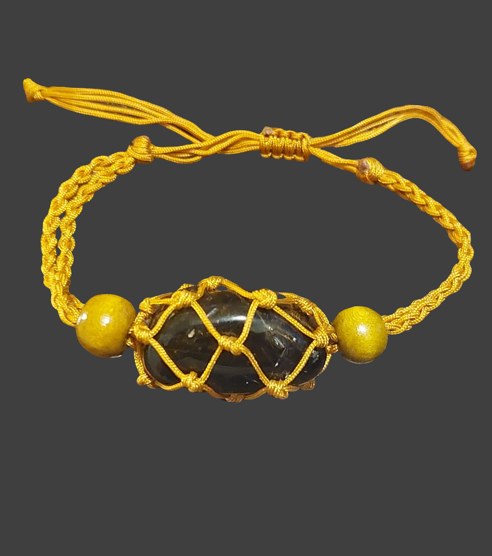 A yellow Macrame tumbled stone bracelet displayed on a clear stand against a beige background.