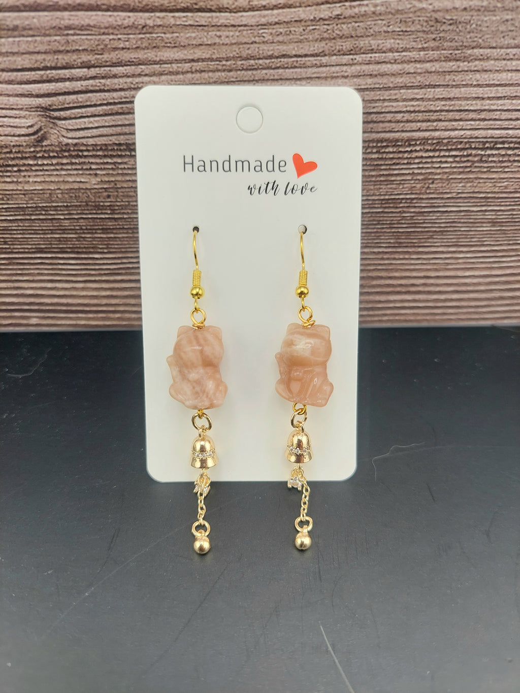 Pair of earrings on a 'Handmade with Love' card against a wooden background