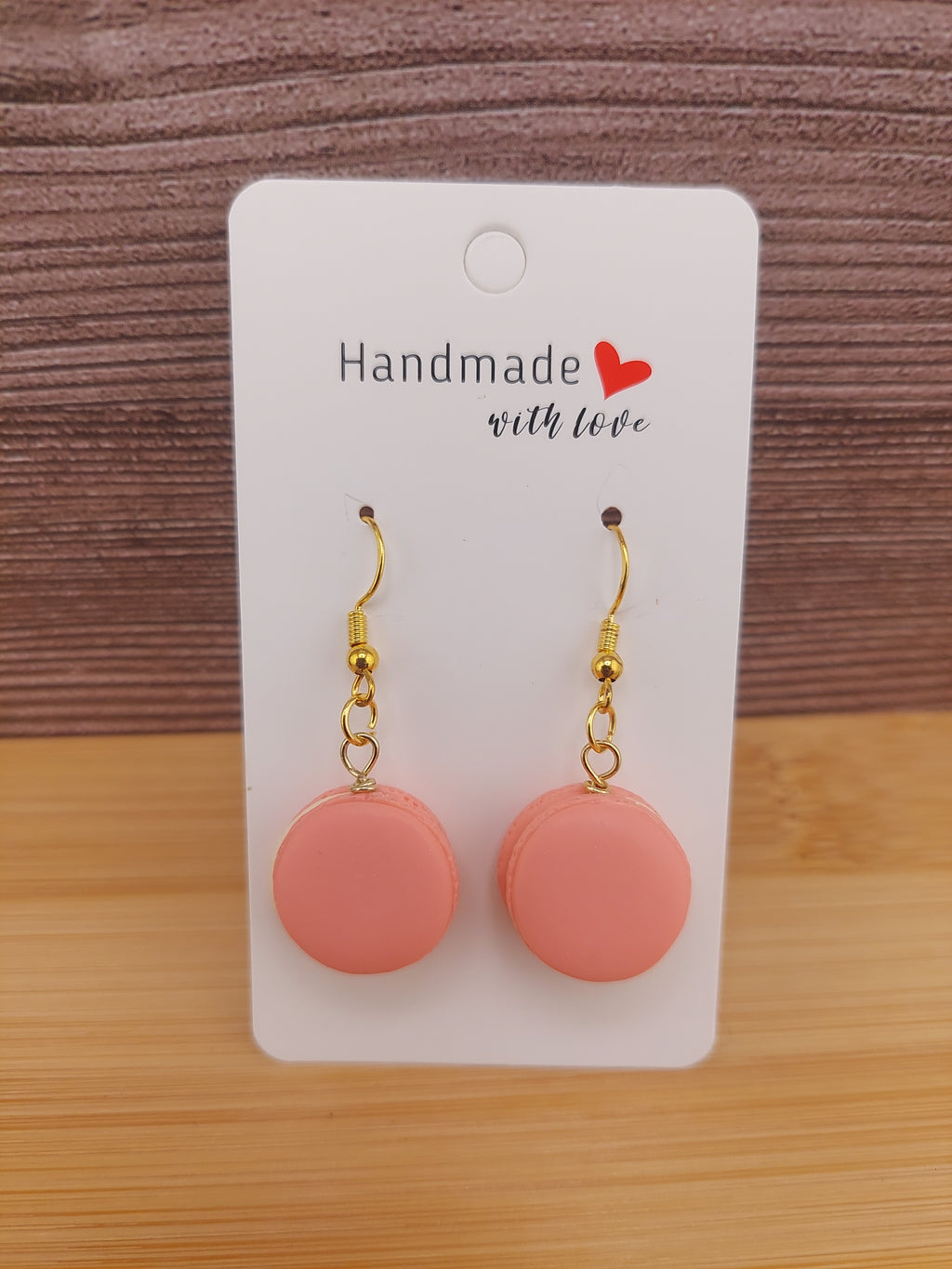 Pink earrings on a 'Handmade with Love' card against a wooden background