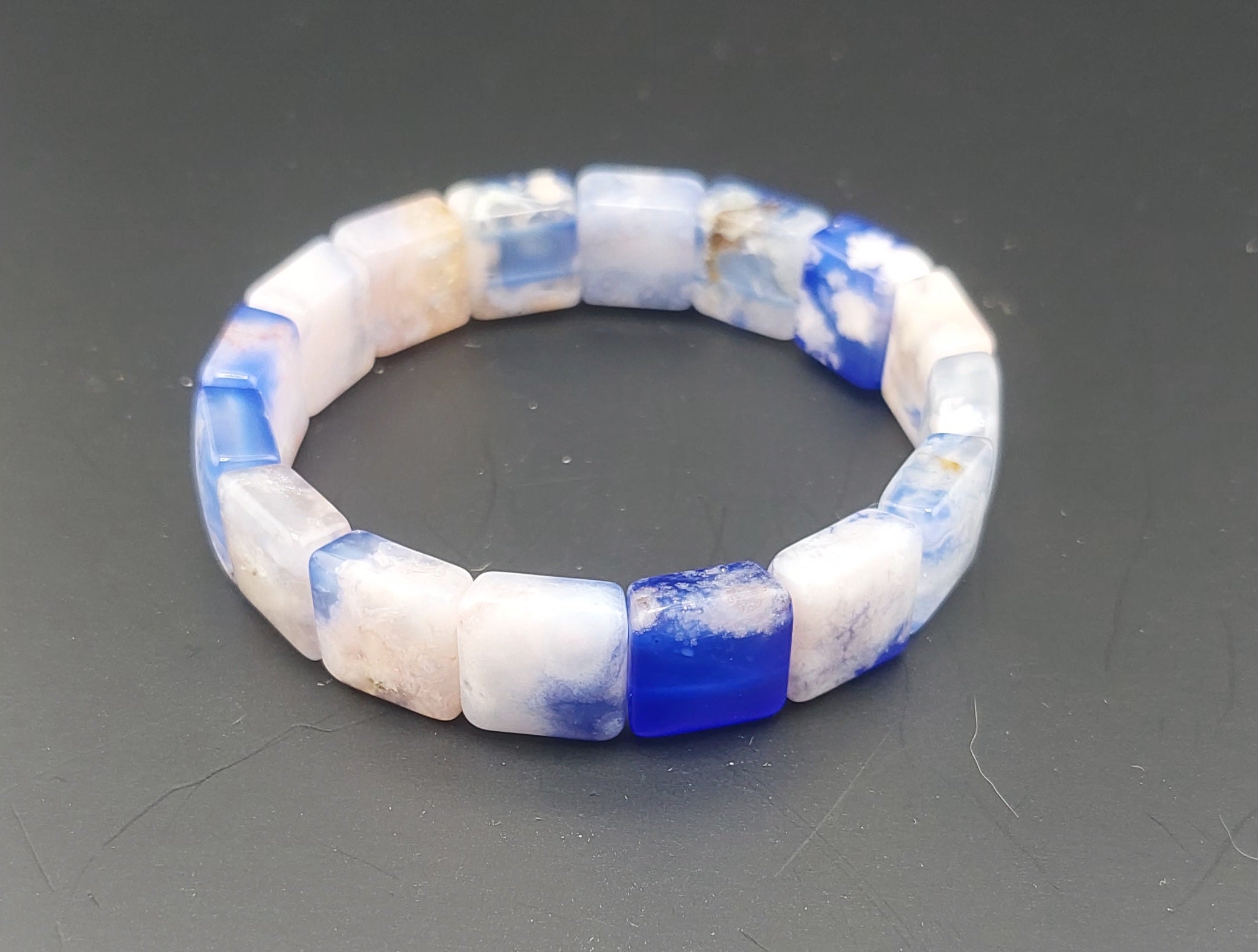 Beaded bracelet with blue and white beads on a gray background