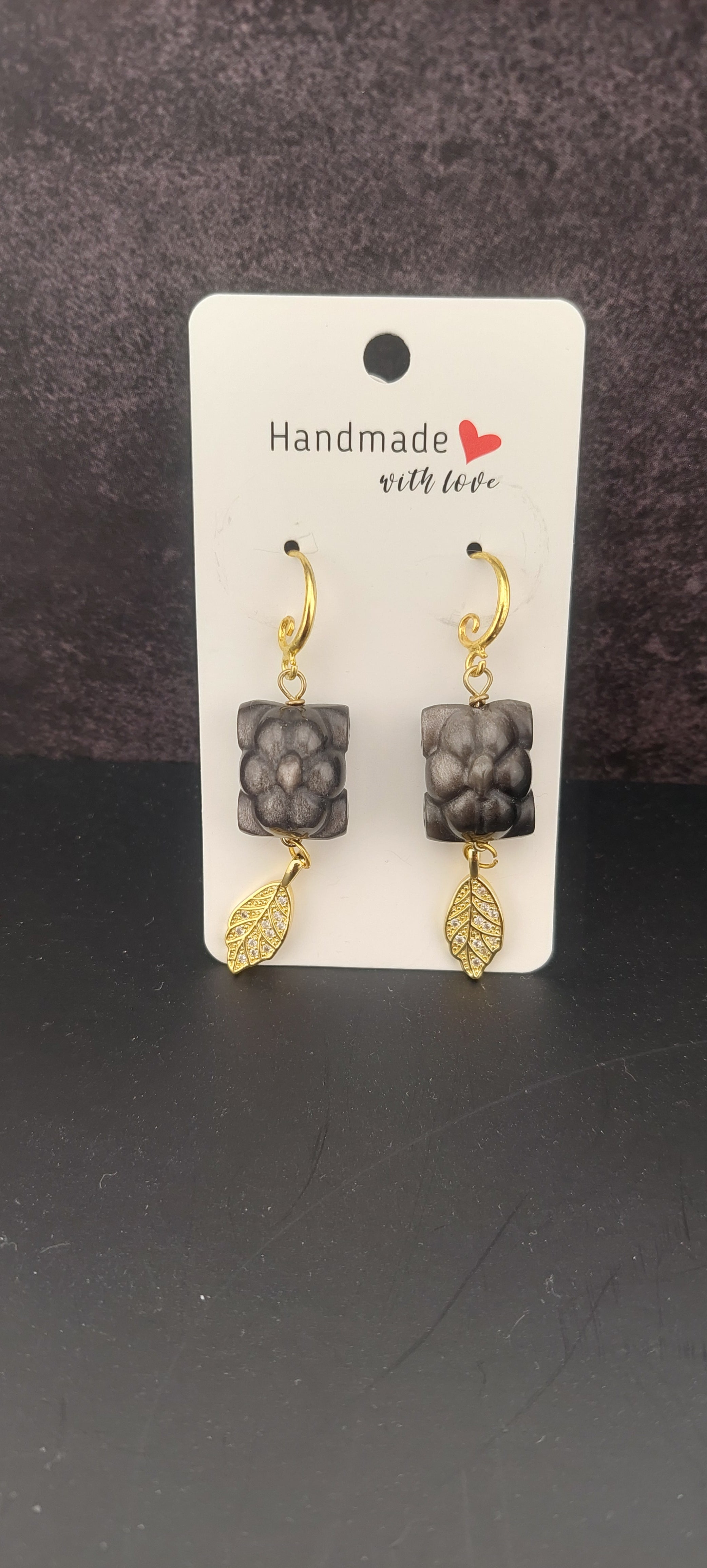Set of gold and silver earrings on a 'Handmade with Love' card against a dark background