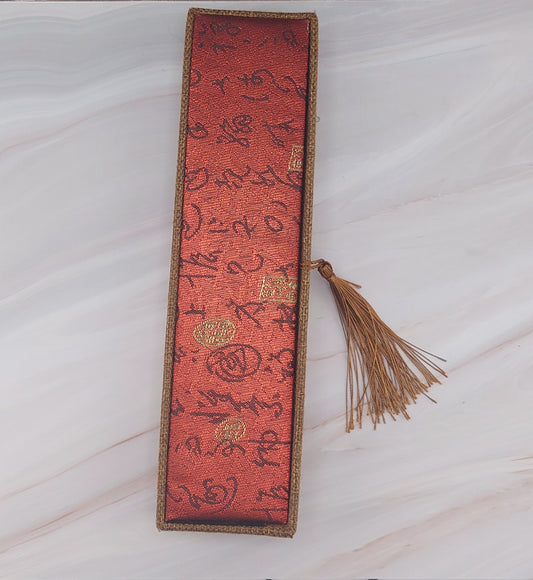 A red and gold patterned jewelry box with a tassel on the front.