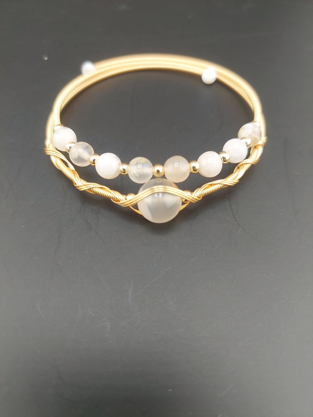Gold bangle with embedded stones on a dark background