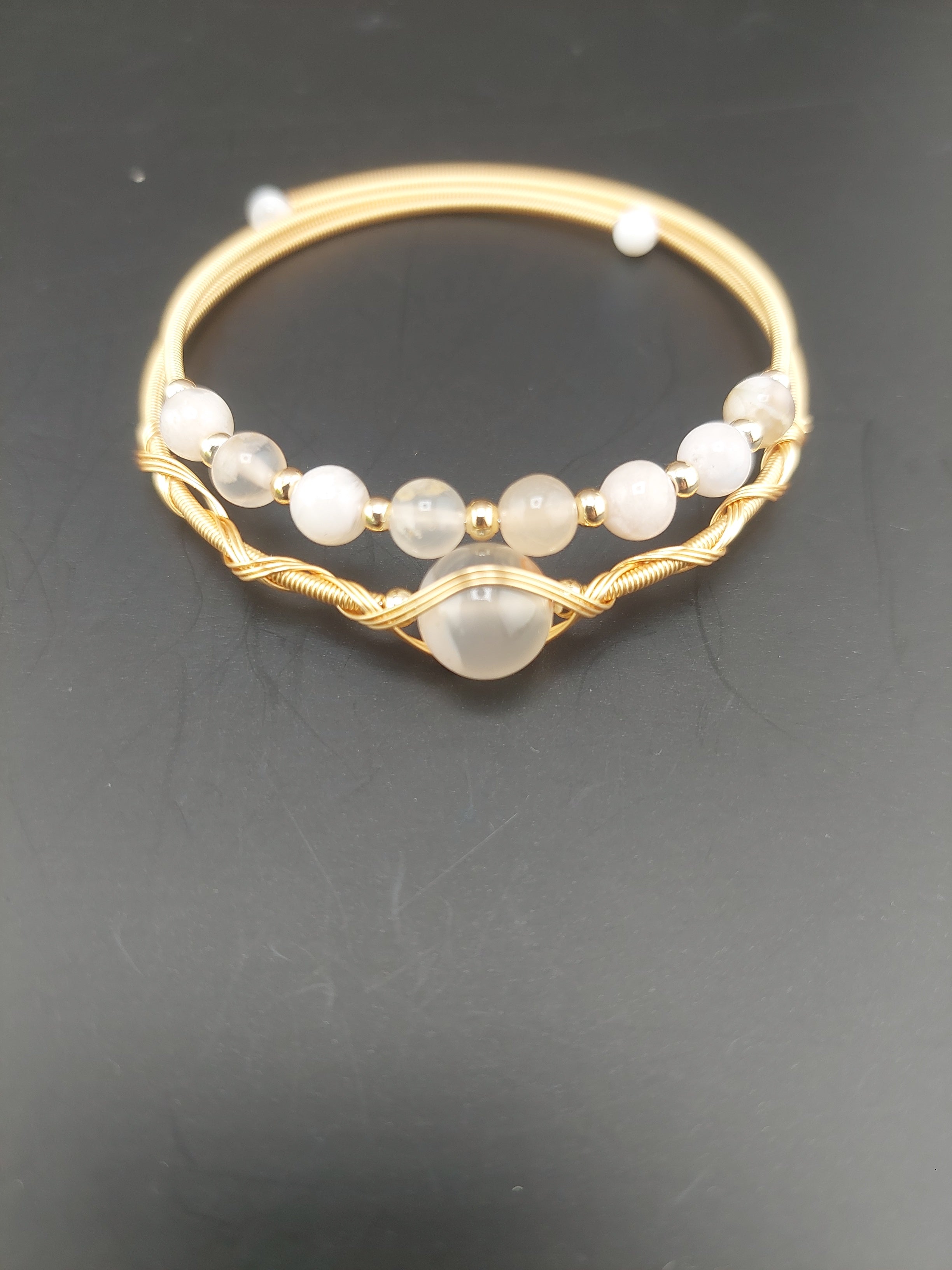 Gold bangle with embedded stones on a dark background