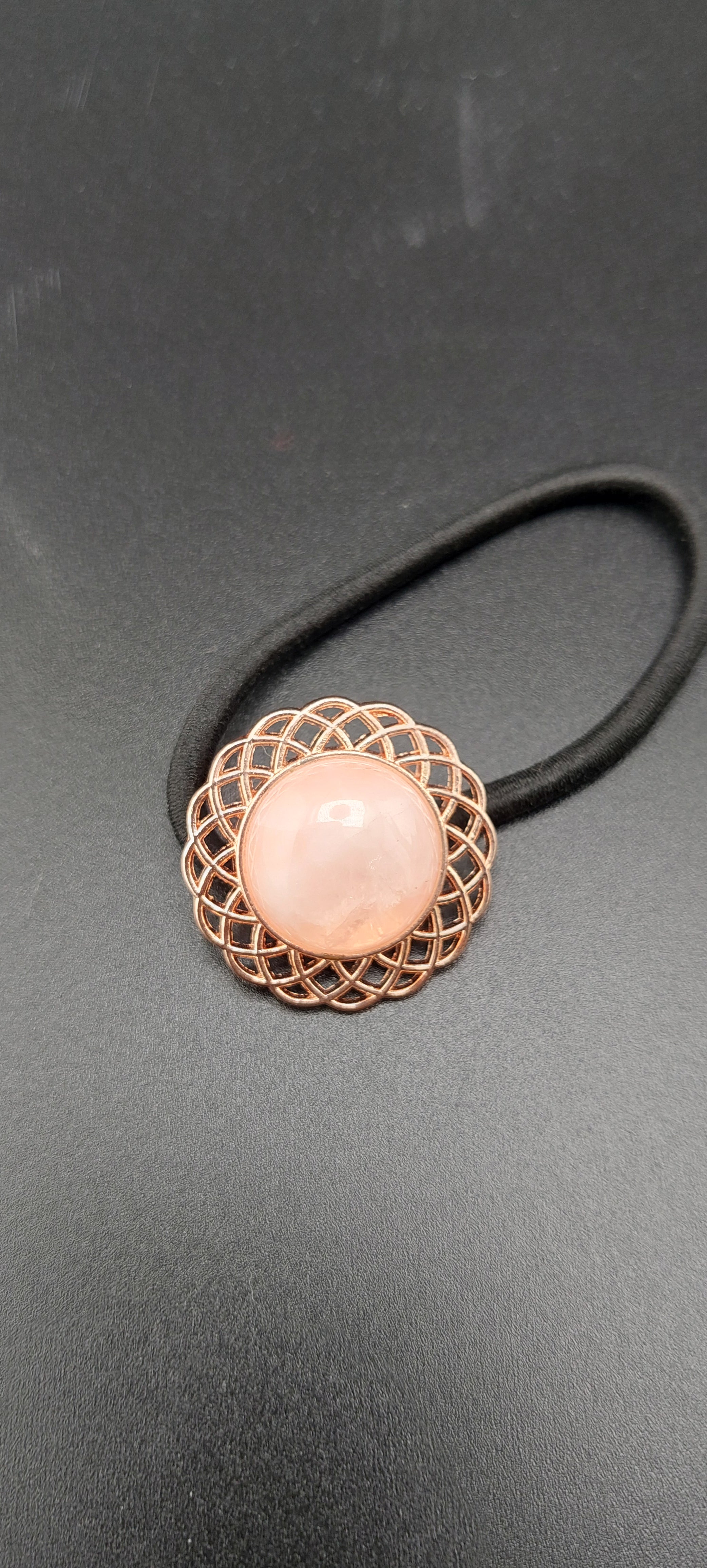 A set of rose gold hair ties with multicolored gemstones and intricate designs on a dark background.
