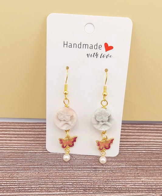 Pair of earrings with floral and butterfly designs on a 'Handmade with Love' card.
