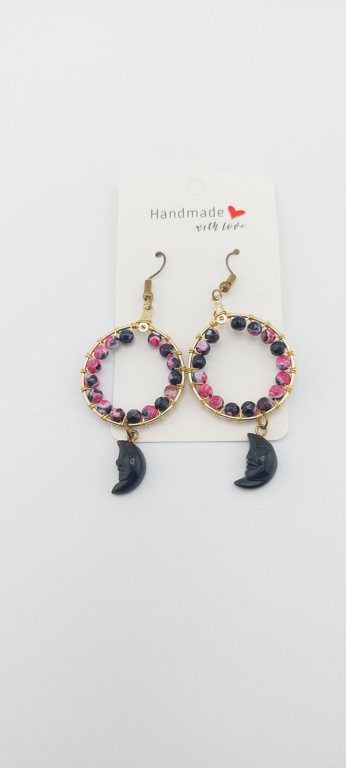 A pair of half moon hoop earrings with multicolored beads and a gold-colored hoop, displayed on a white card with a 'Handmade' sticker.