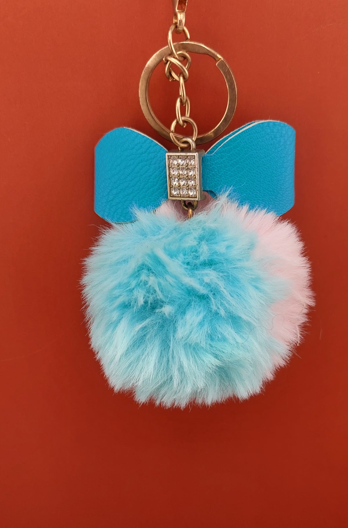 Keychain with blue bow and fluffy pom-pom on a red background