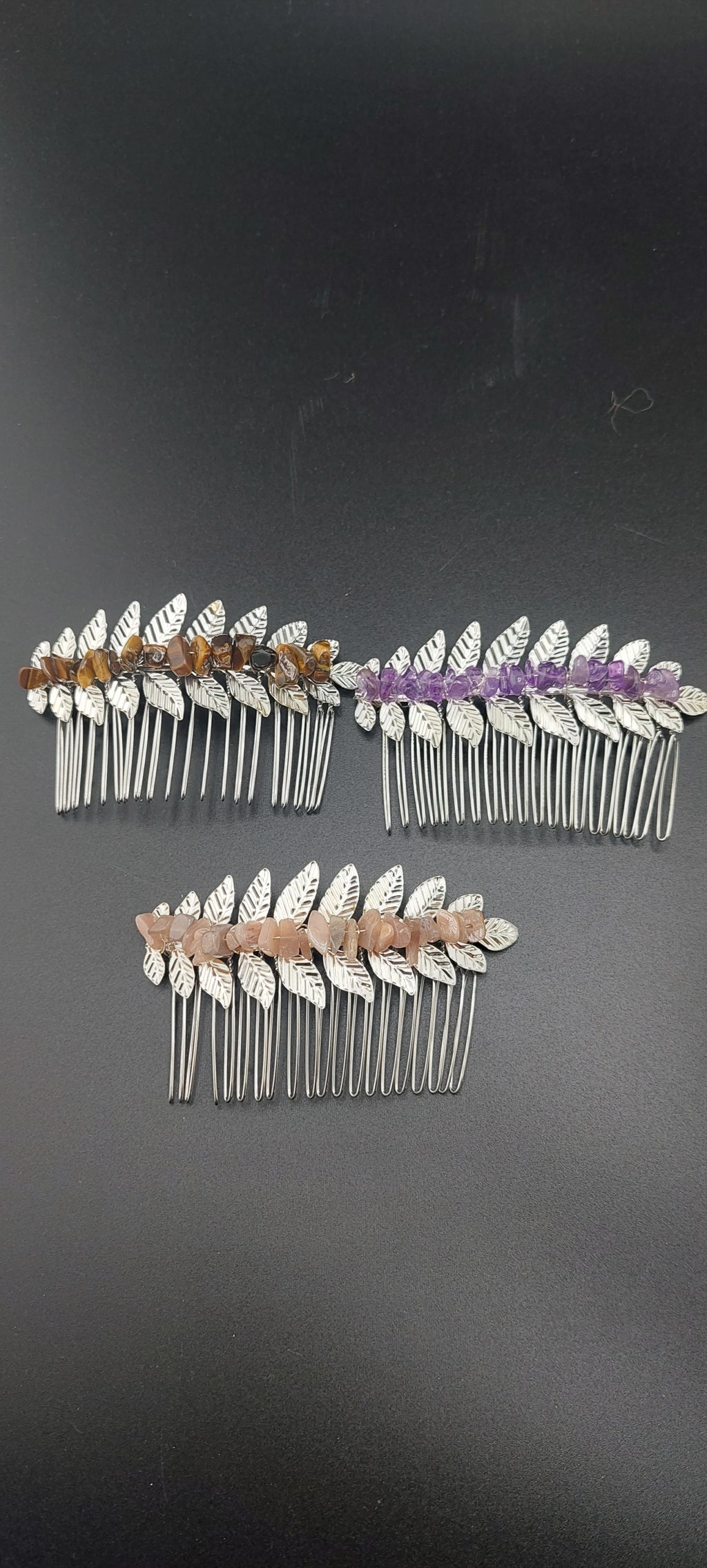 A collection of silver leaf hair clips in varying colors, displayed on a dark background.
