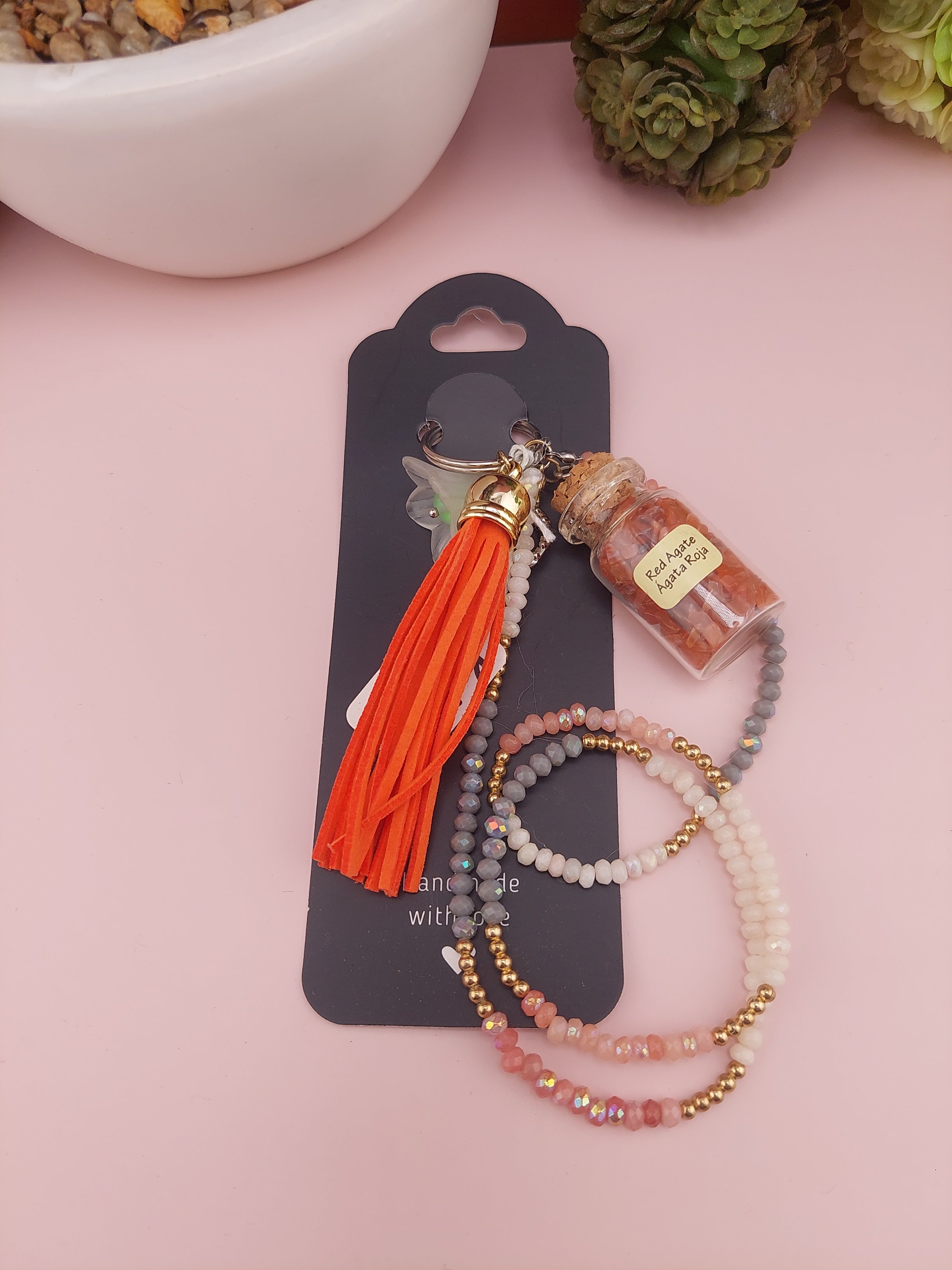Set of beaded bracelets with a tassel on a pink background