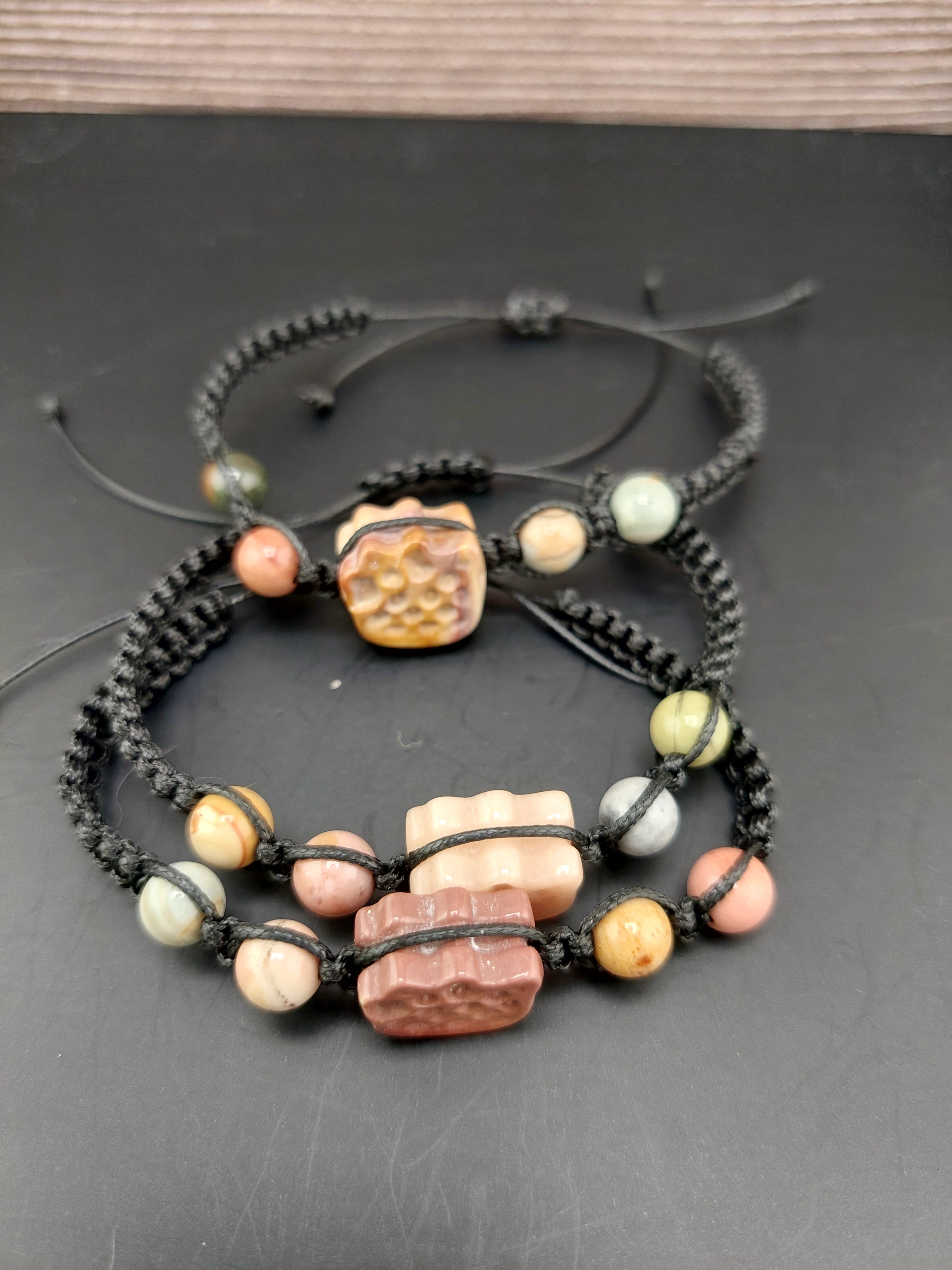 Stack of beaded bracelets with natural stone beads on a dark surface