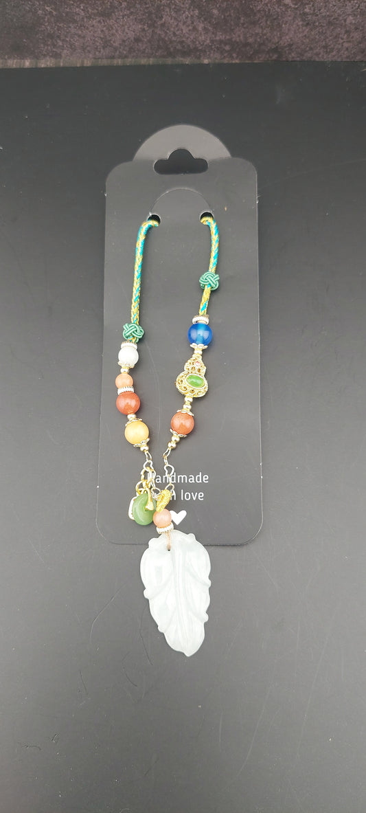 Colorful beaded bracelet on a black card with a white leaf design