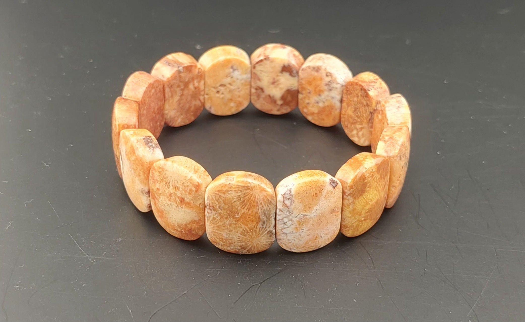 Beaded bracelet with brown and beige stones on a dark gray background