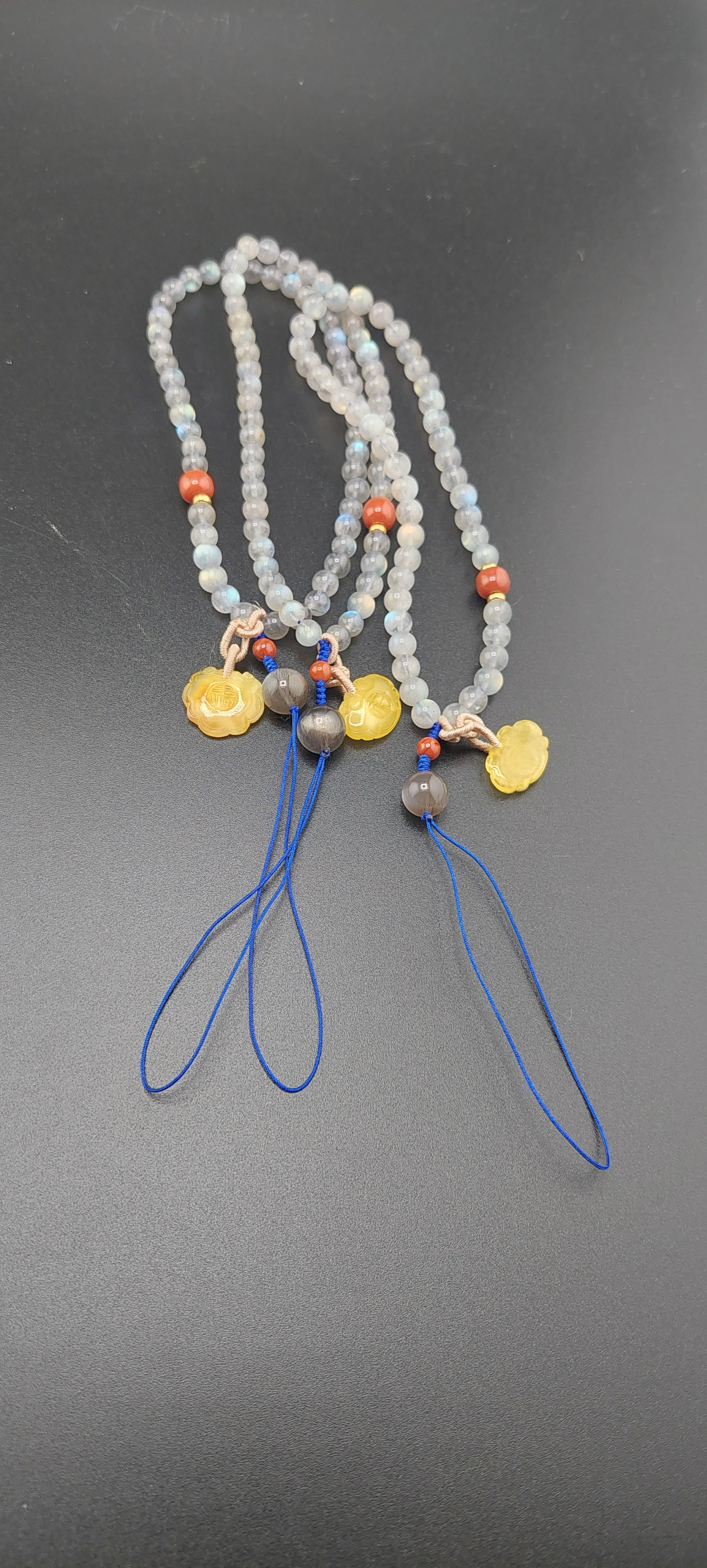 A labradorite car hanger with blue strings, featuring small round beads and metal pendants in silver and gold colors.
