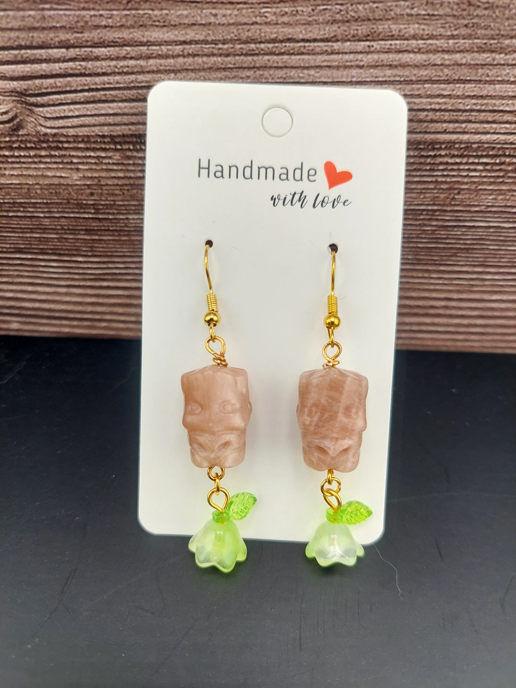Pair of earrings on a 'Handmade with Love' card against a wooden background