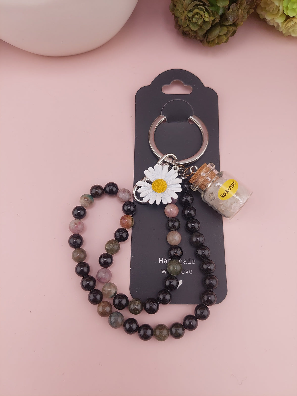 Beaded necklace with a keychain and daisy charm on a pink background