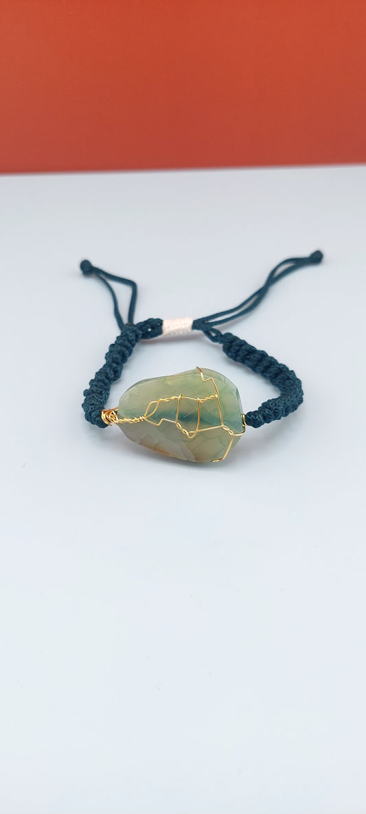 An elegant crackled agate stone macrame bracelet with blue and green strings, displayed against a two-tone background.