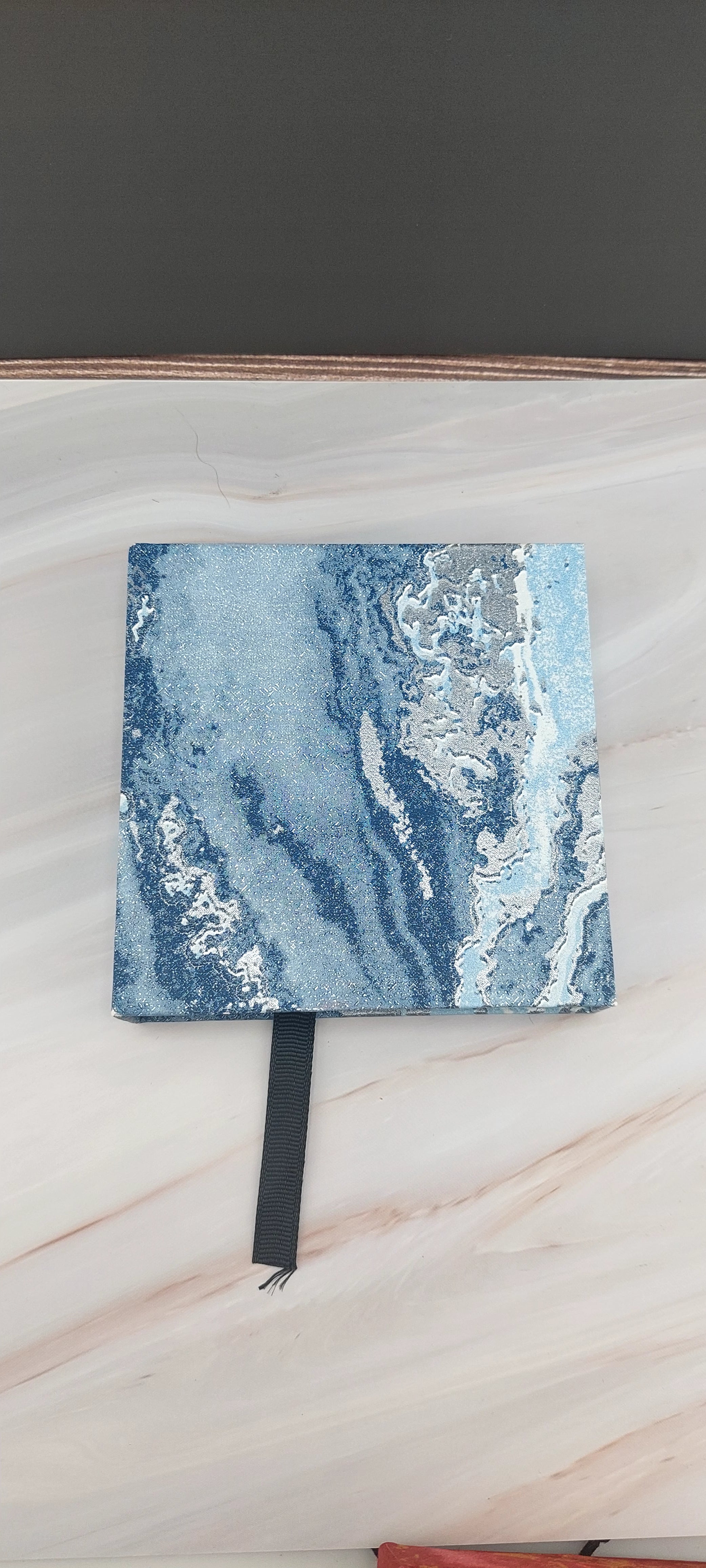 A red and gold bangle box with a sticky texture on the inside, placed on a marble surface.