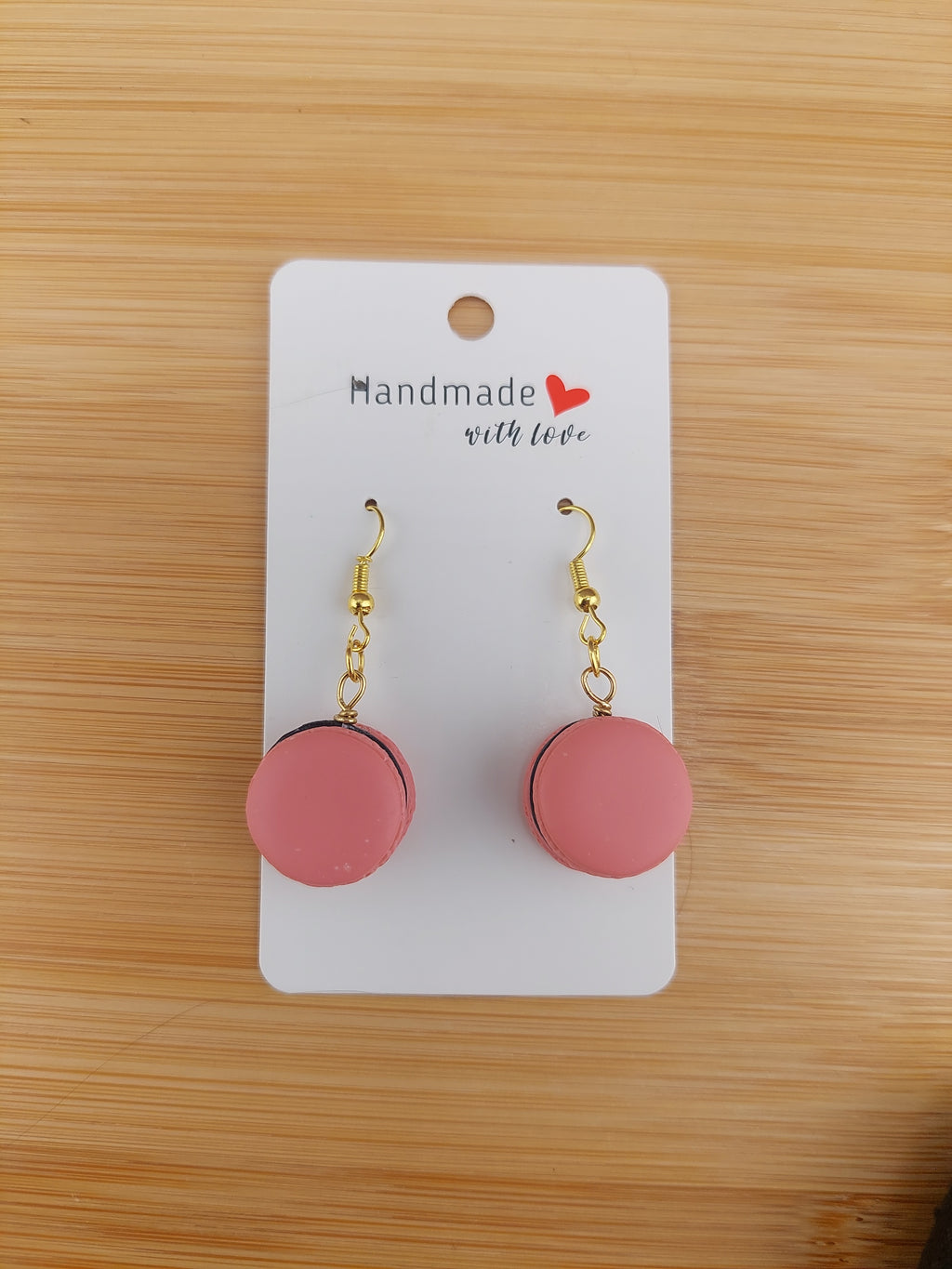 Pink earrings on a white card with 'Handmade with Love' text, placed on a wooden surface.