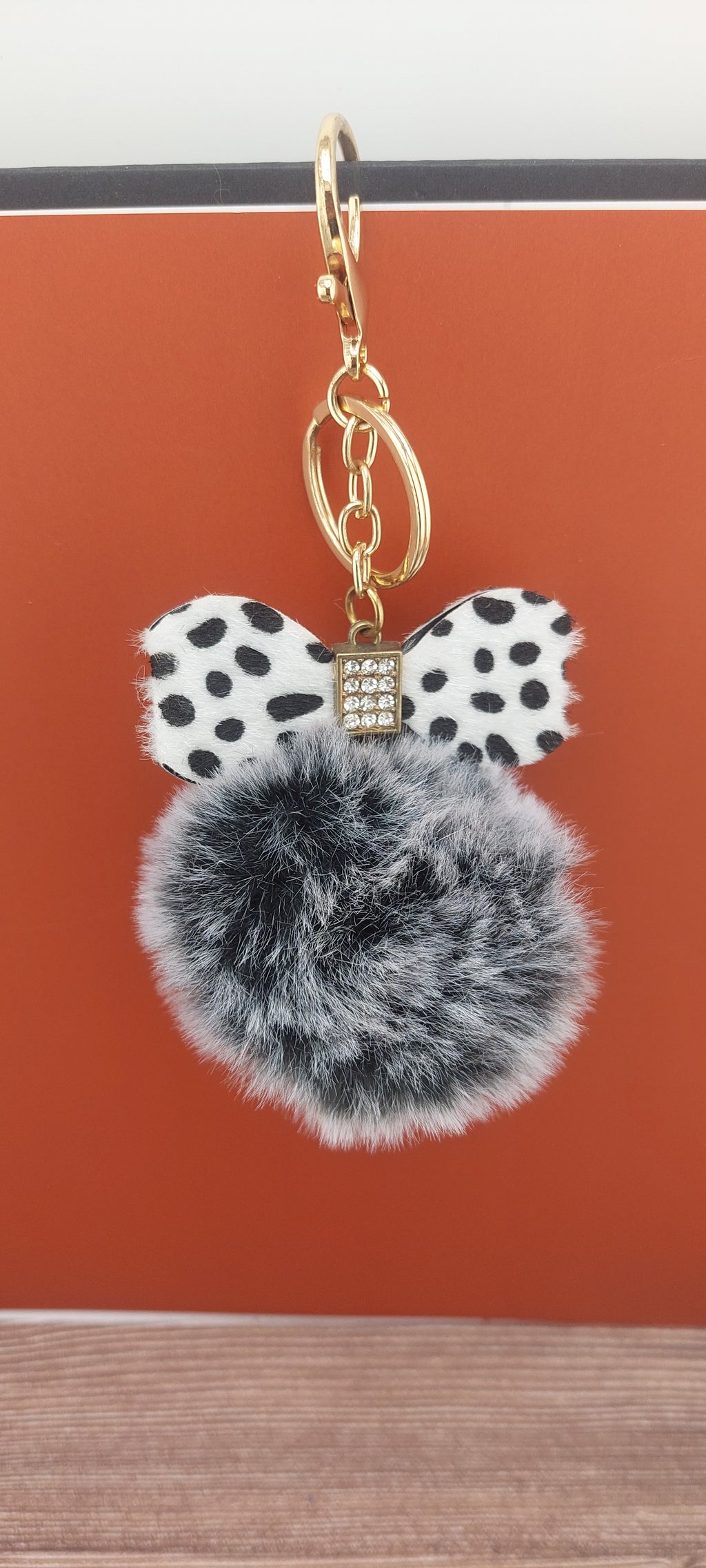 Keychain with polka dot bow and gray pom-pom on a red background