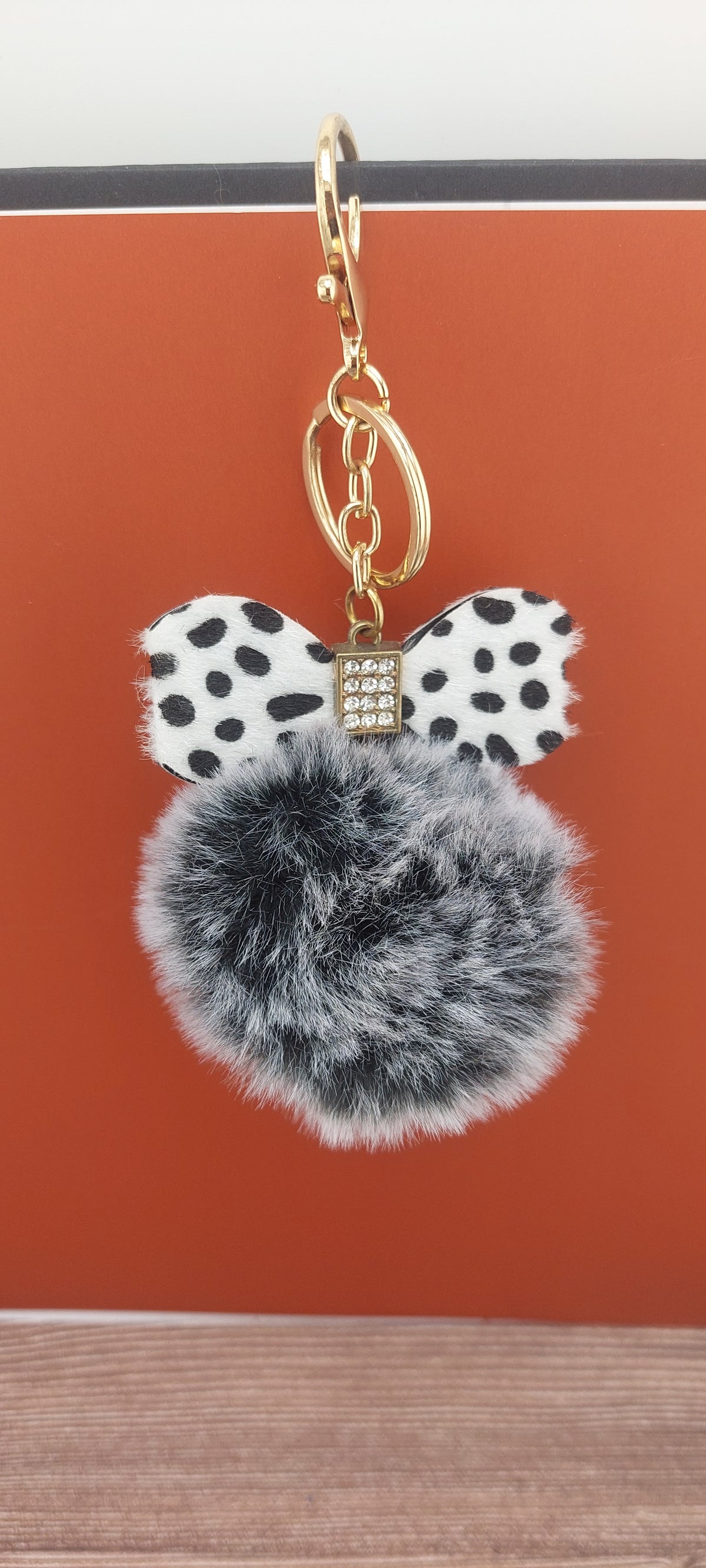 Keychain with polka dot bow and gray pom-pom on a red background