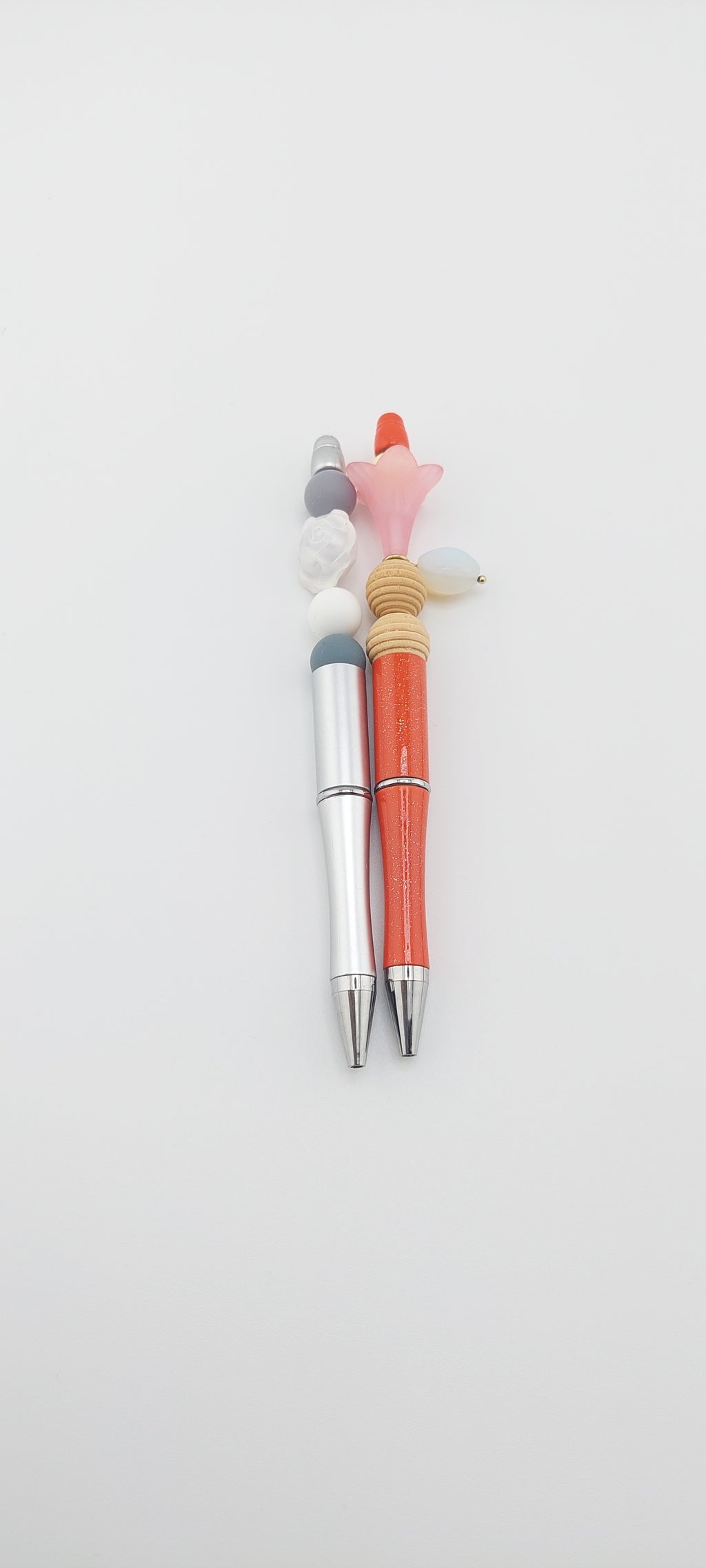 Two pens with multicolored caps placed side by side on a white surface.
