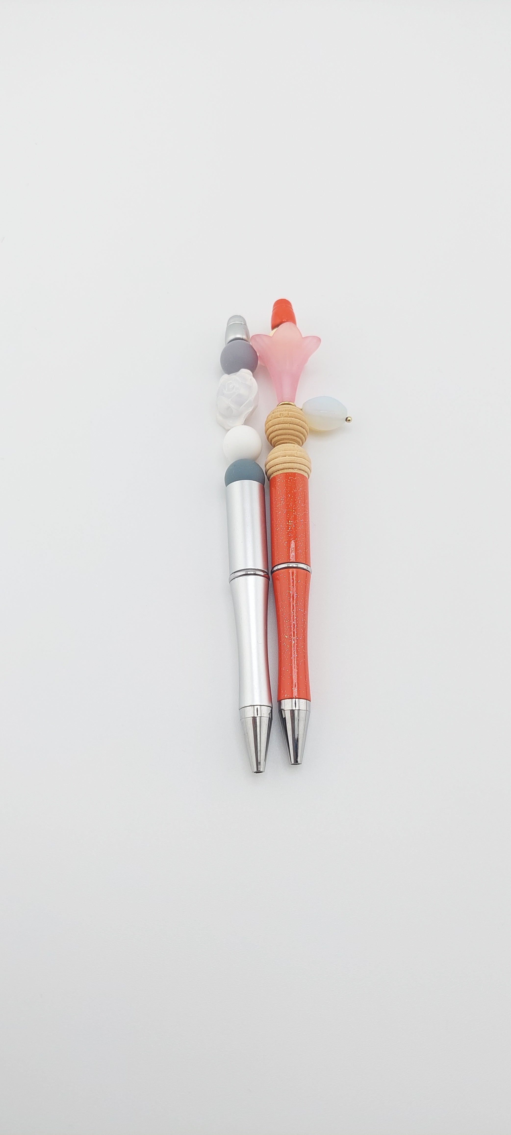 Two pens with multicolored caps placed side by side on a white surface.